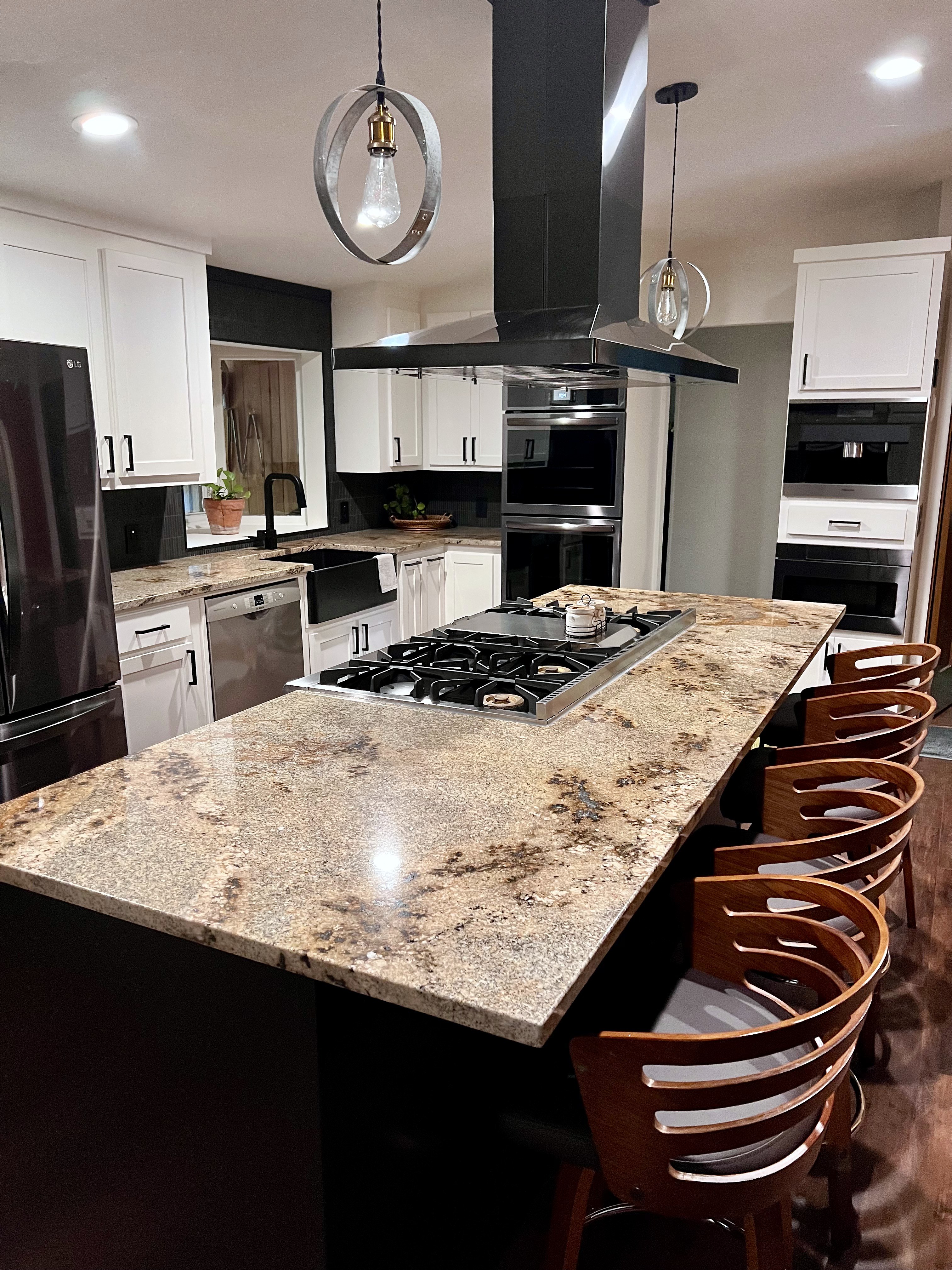 Buckhorn kitchen after — full room view with black island, granite countertop, dual pendant lights, white shaker cabinets and black appliances