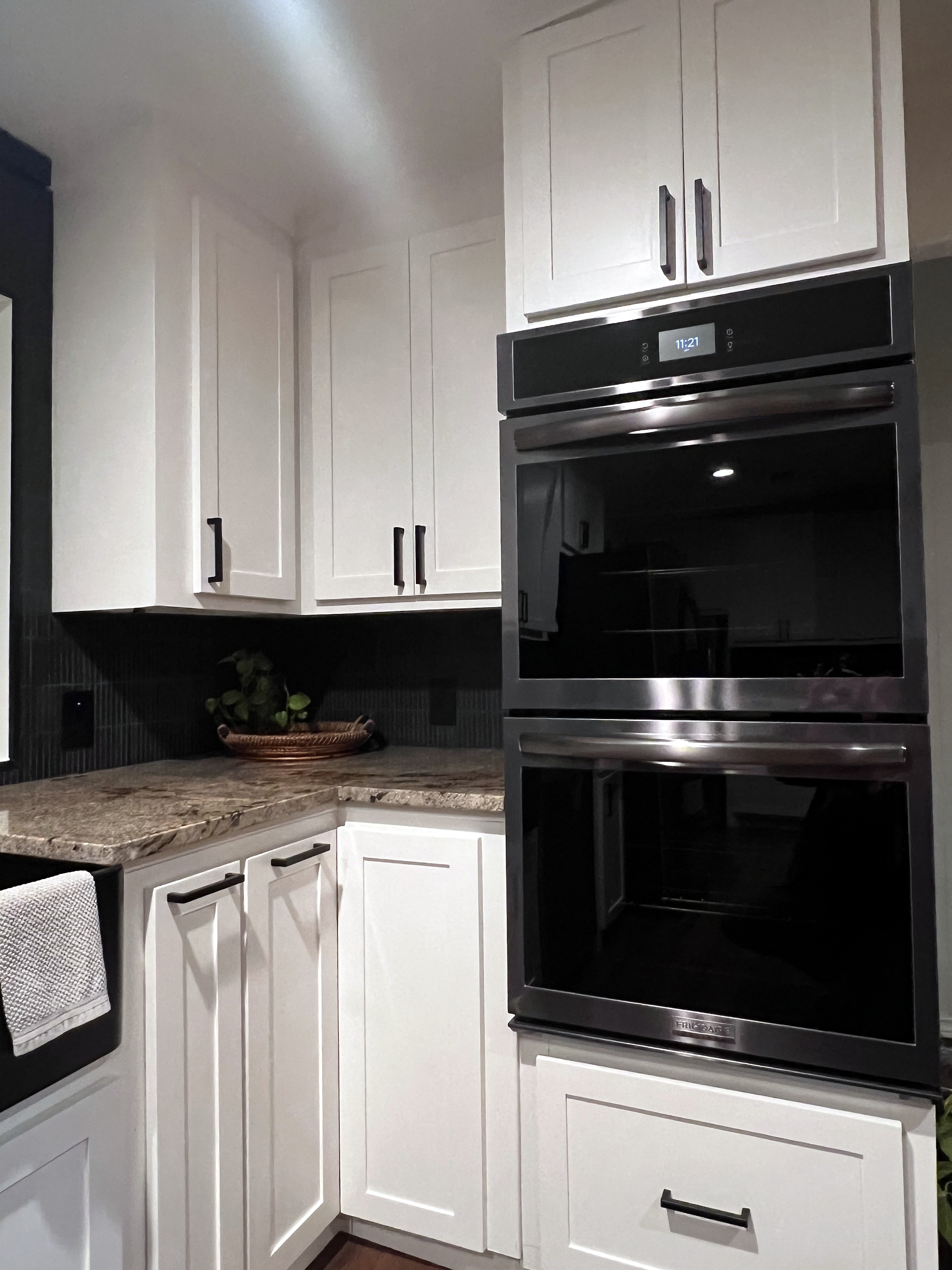 Buckhorn kitchen after — corner detail with new double wall oven in white shaker cabinetry, black linear backsplash tile and granite countertop