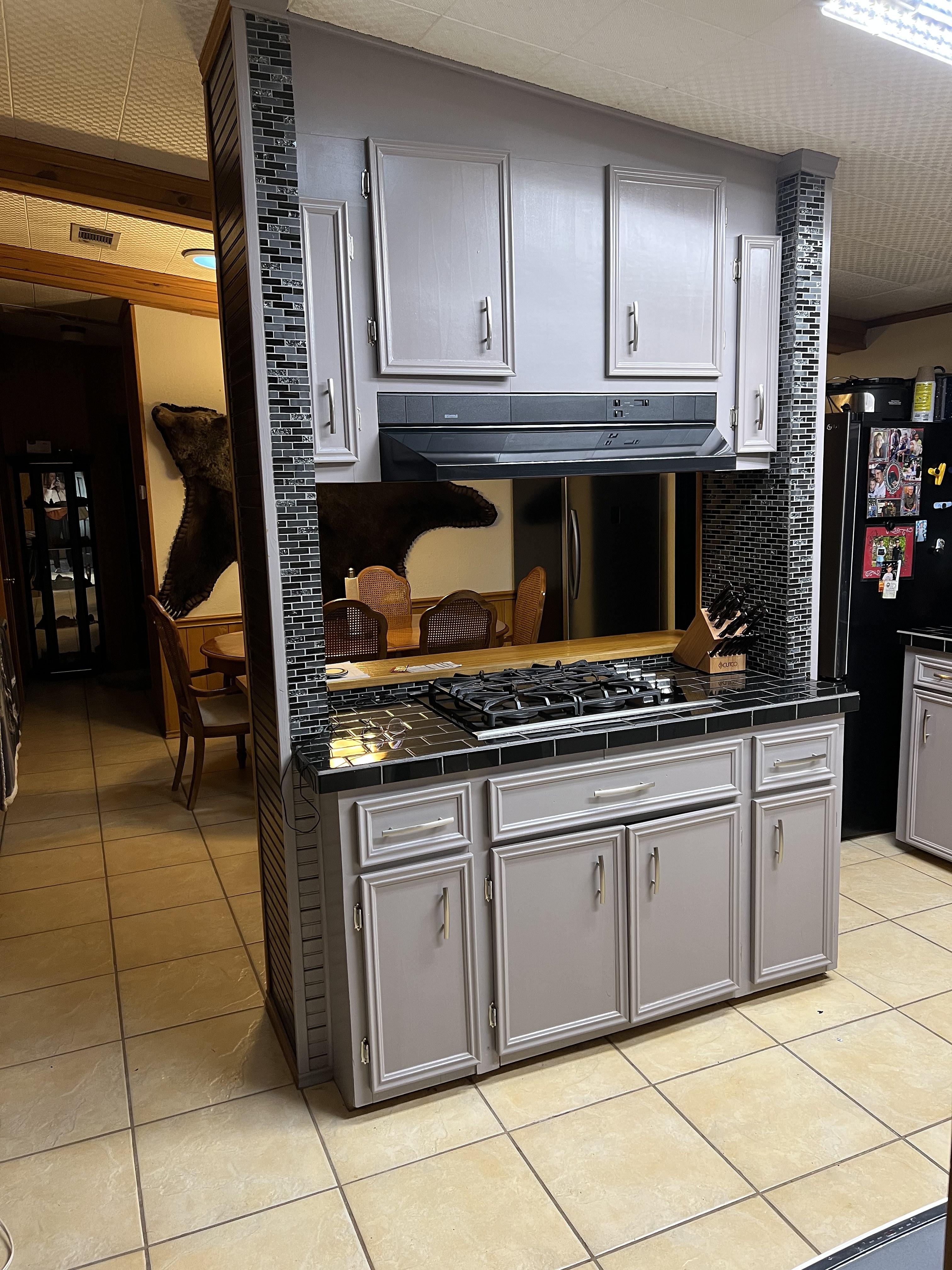 Buckhorn kitchen before — original cooktop peninsula tower with gray cabinets, mosaic tile columns and range hood before island renovation