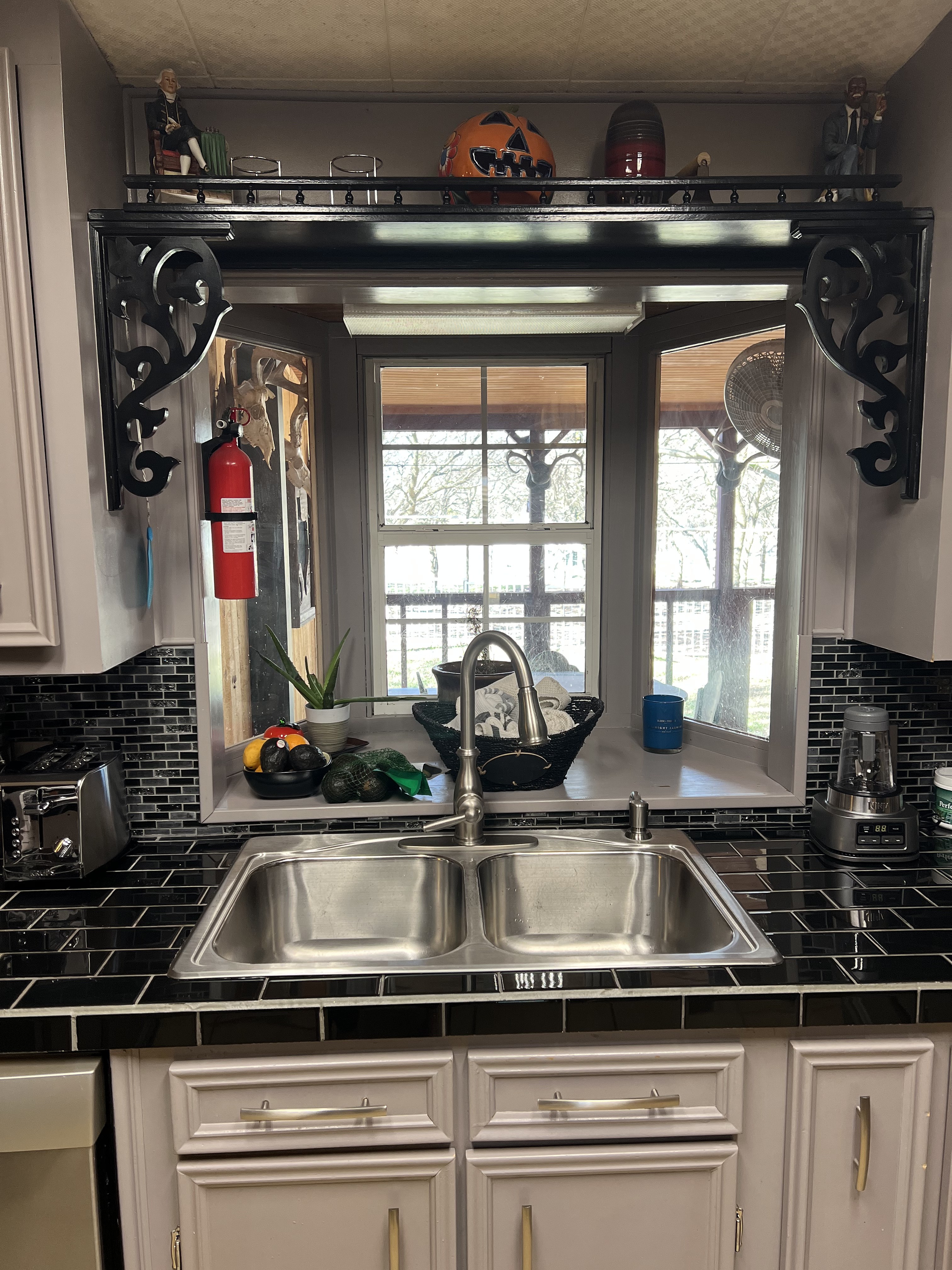 Buckhorn kitchen before — original double stainless sink with decorative shelf brackets, bay window and black tile countertop