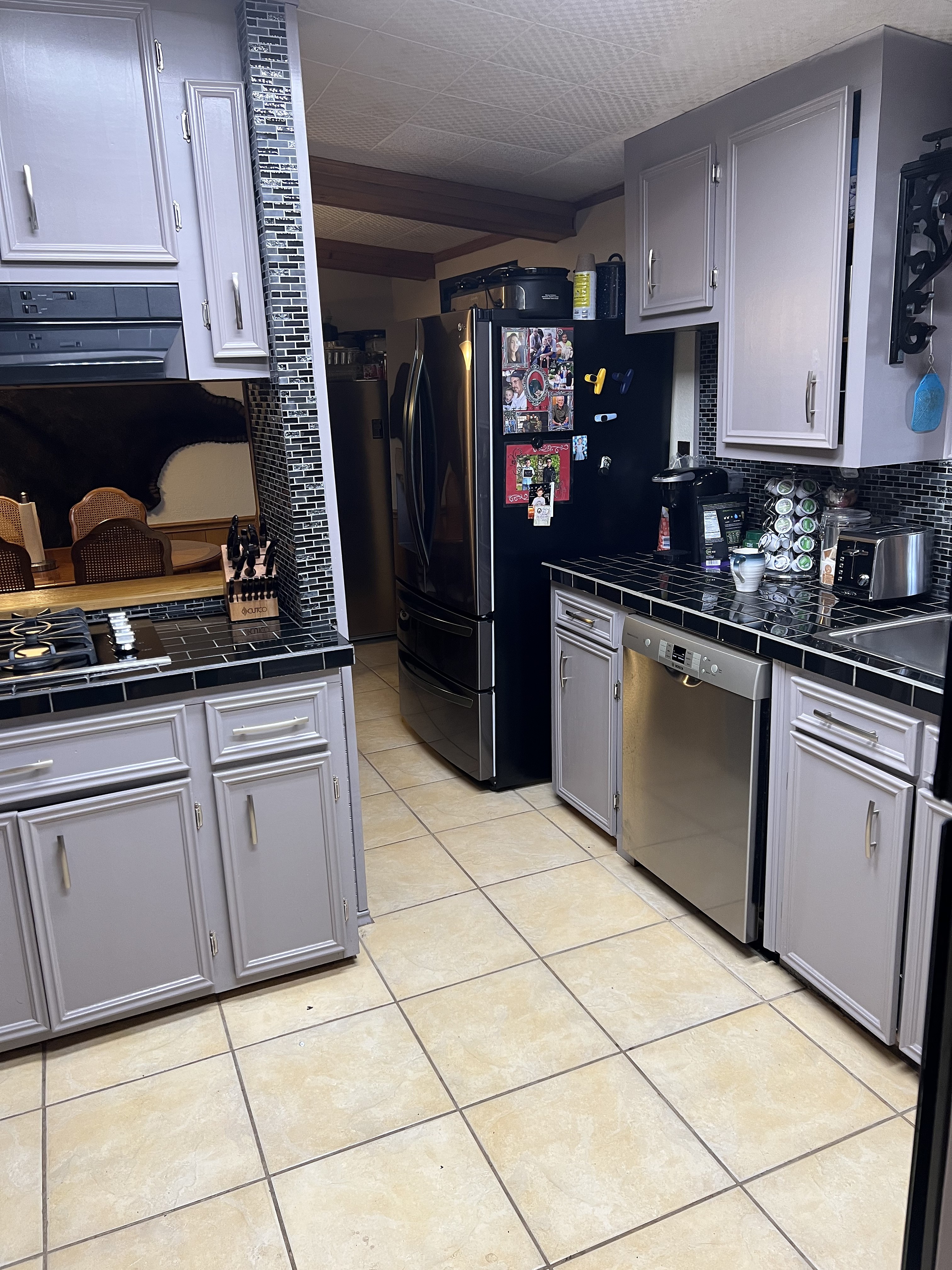 Buckhorn kitchen before — perimeter wall with gray cabinets, original black tile counters and stainless refrigerator