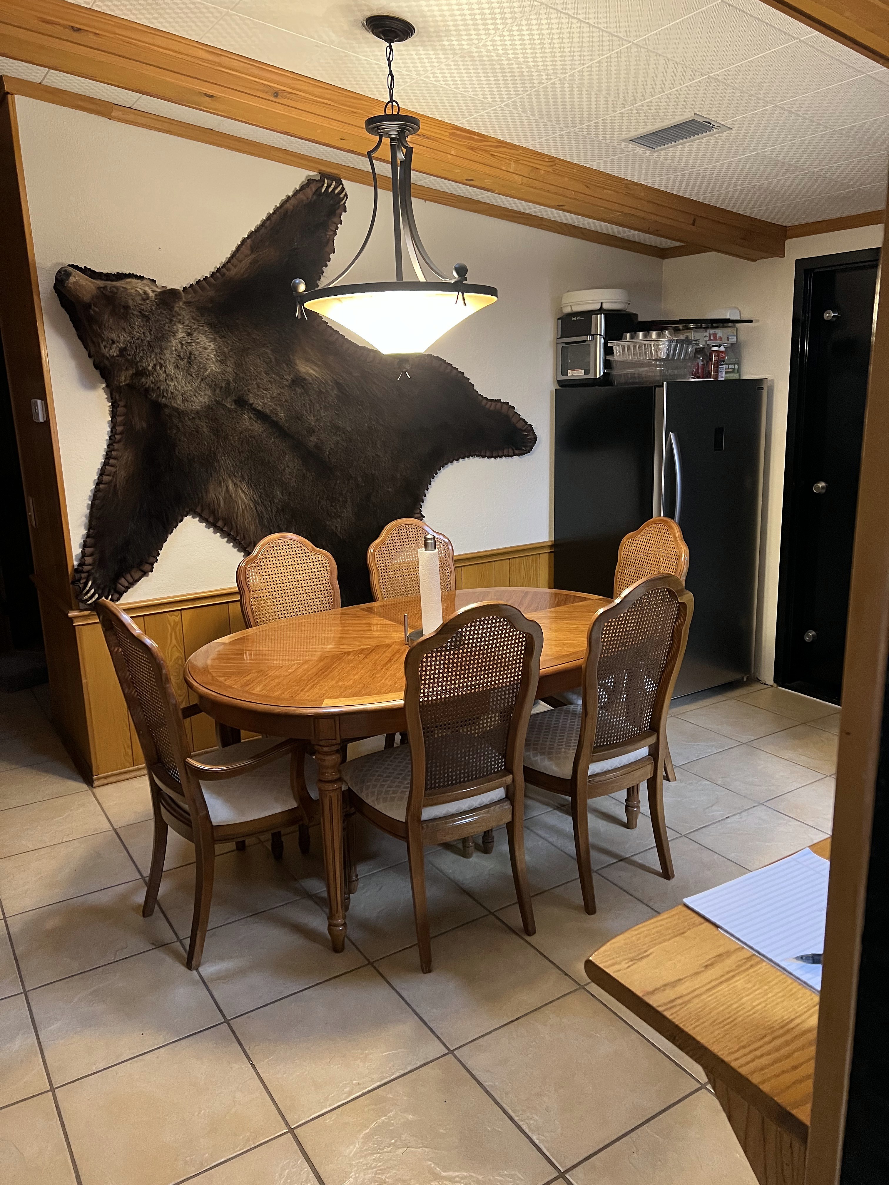 Buckhorn dining area before — original round dining table with cane chairs and pendant light