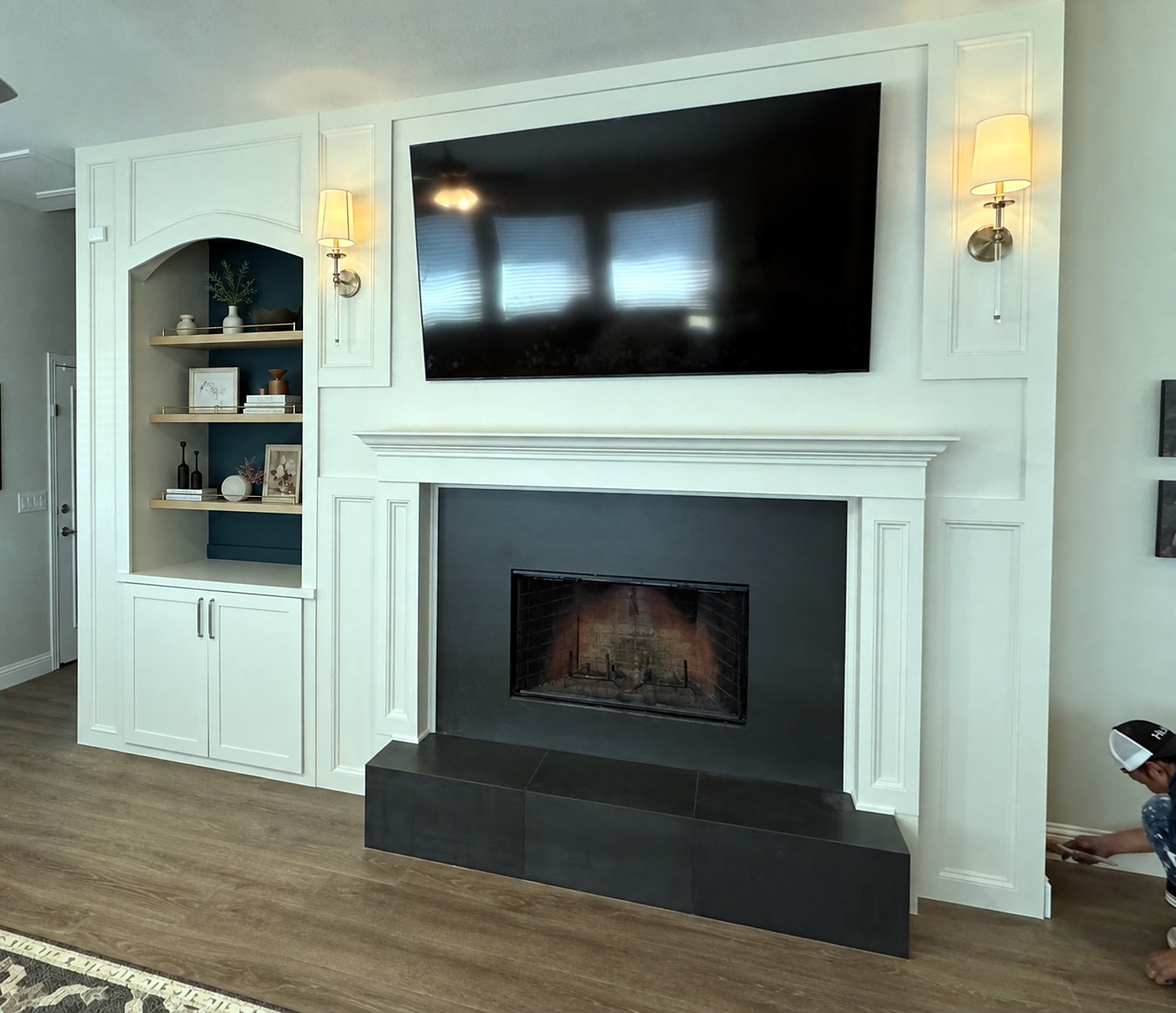 Half Moon after — wide angled view of completed fireplace wall with white millwork, charcoal surround, arched built-in niche with teal backing and styled wood shelves