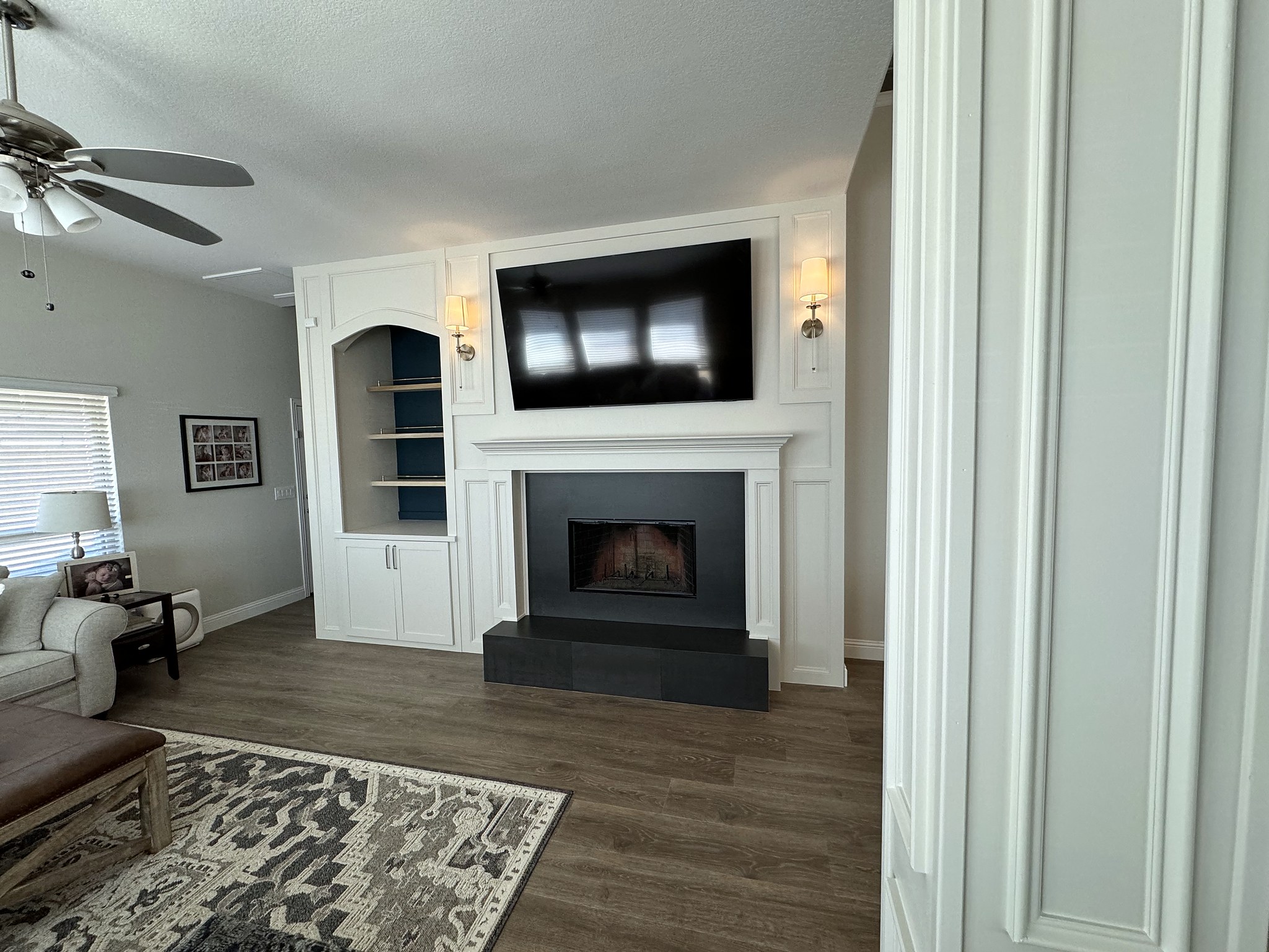 Half Moon after — wide living room view showing completed fireplace wall in context with seating, rug and natural light from adjacent windows