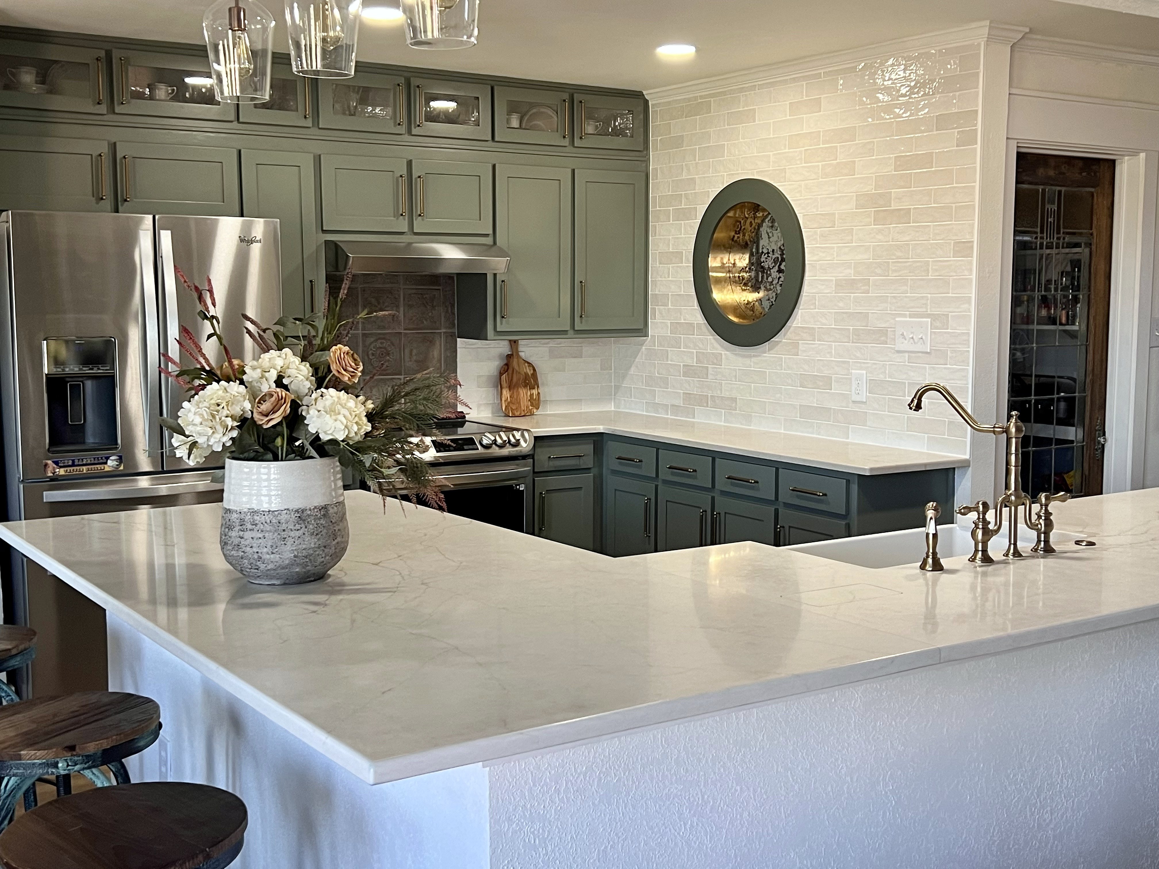 Millbrook kitchen renovation — wide overview with sage cabinets to ceiling, marble island, bridge faucet and round porthole window