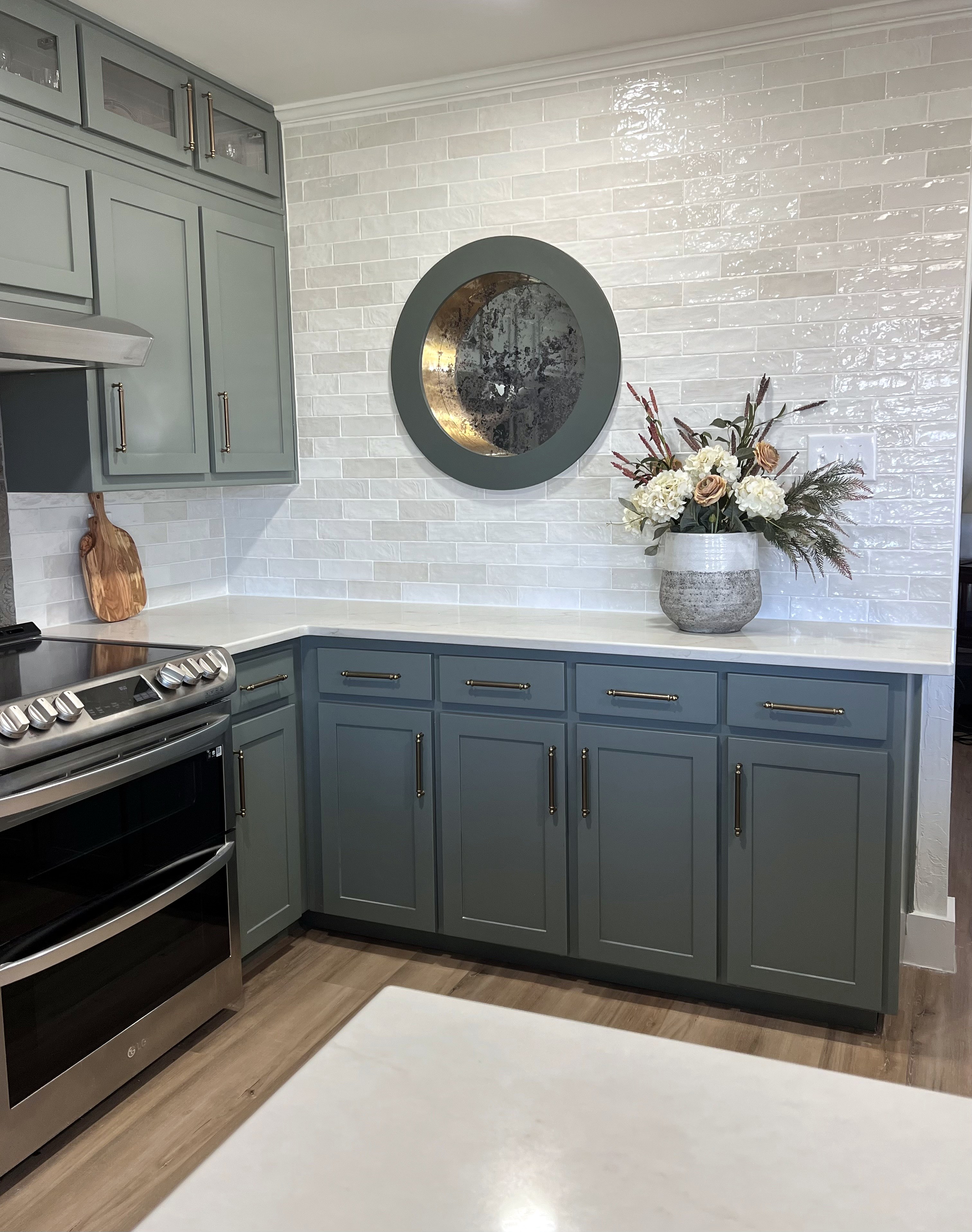 Millbrook kitchen renovation — stove side with cabinetry extending to ceiling, round window and flower arrangement on counter