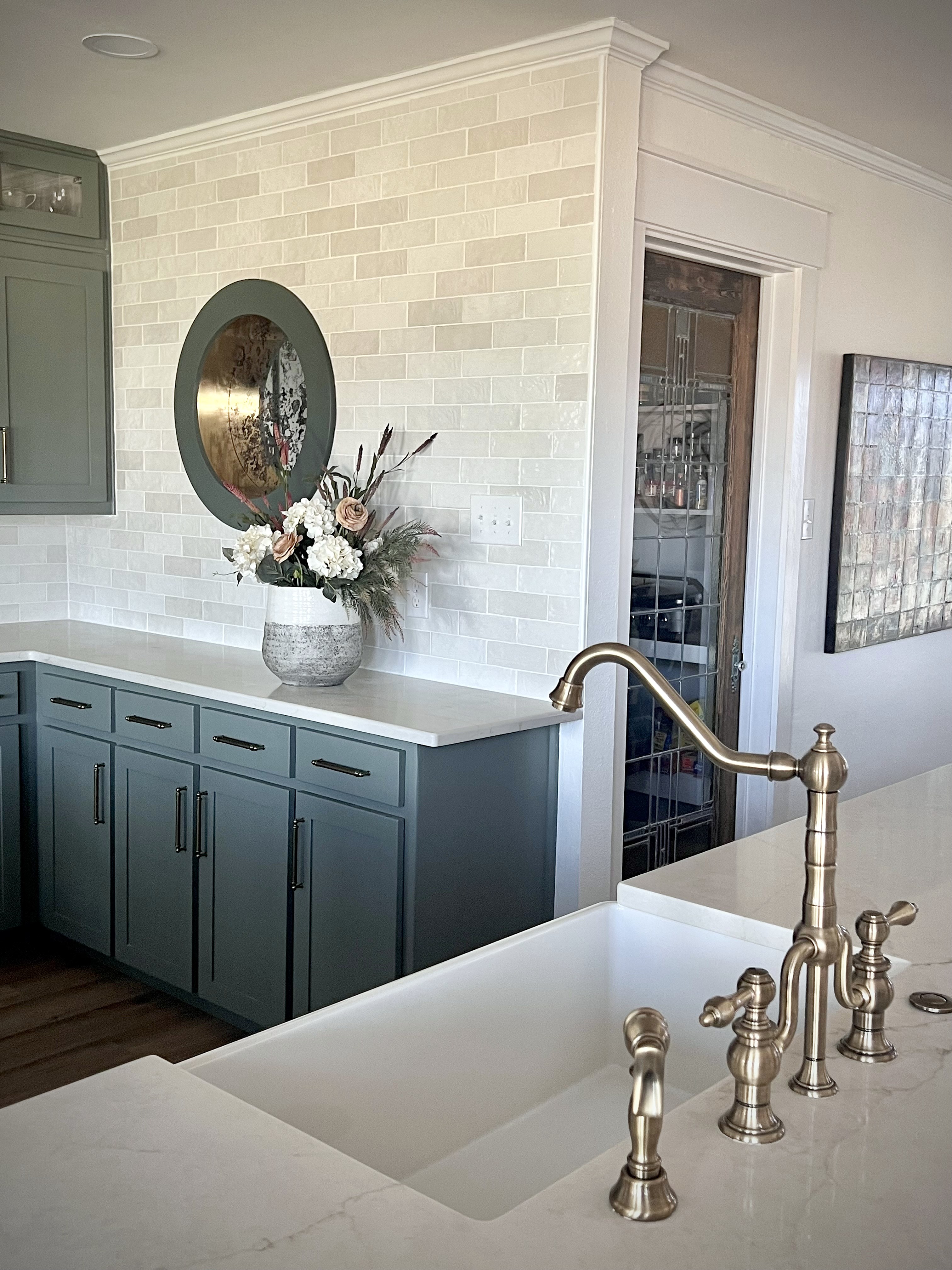 Millbrook kitchen renovation — bridge faucet and farmhouse sink with porthole window and pantry door in background