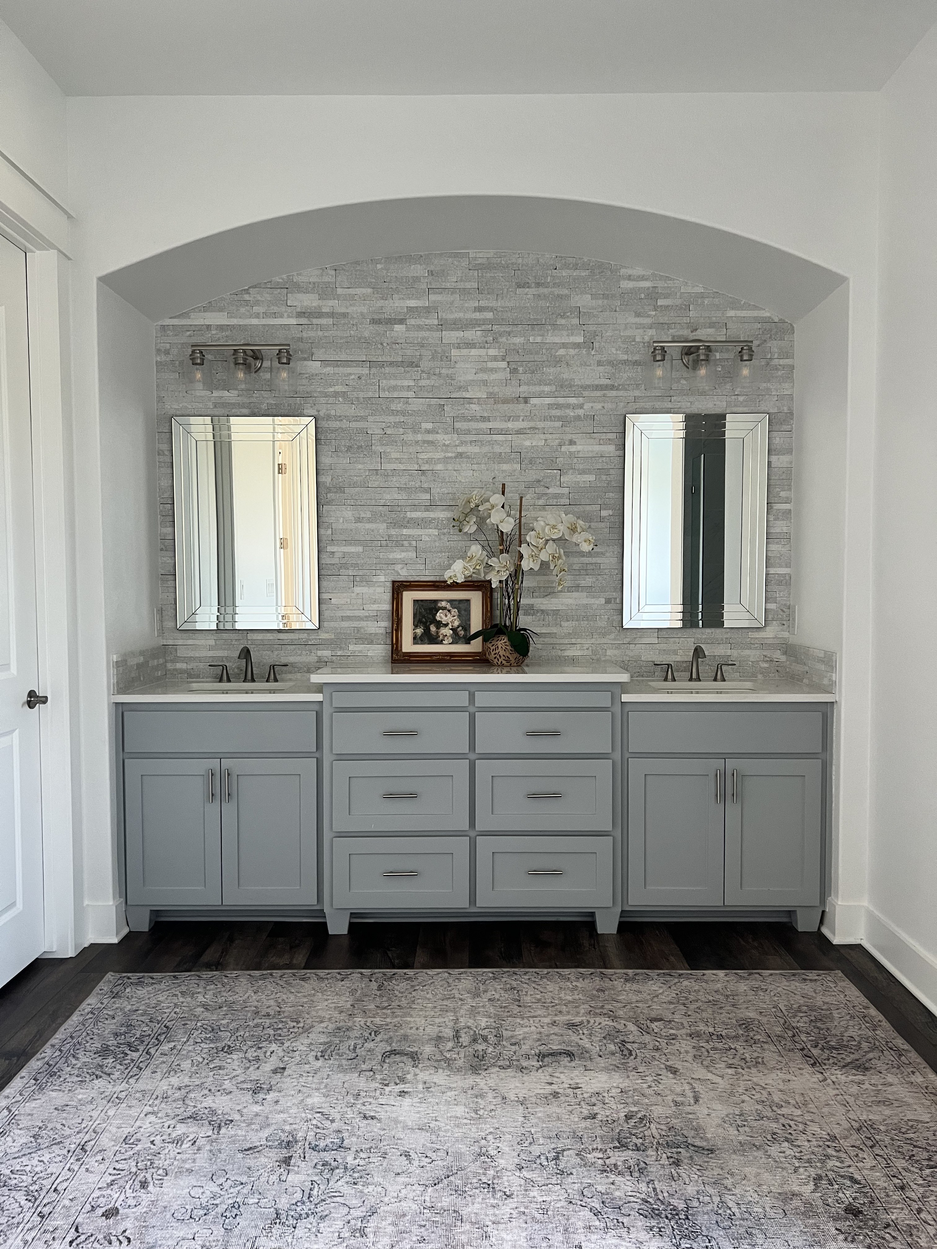 Old Gin primary bathroom — grey double vanity in stone tile arch niche