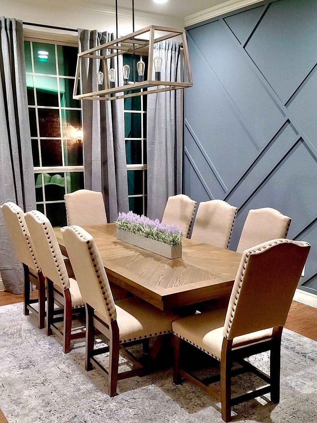 Pamela Lane dining room — geometric slate-blue accent wall, rectangular chandelier, linen chairs and herringbone dining table, 940 Interiors