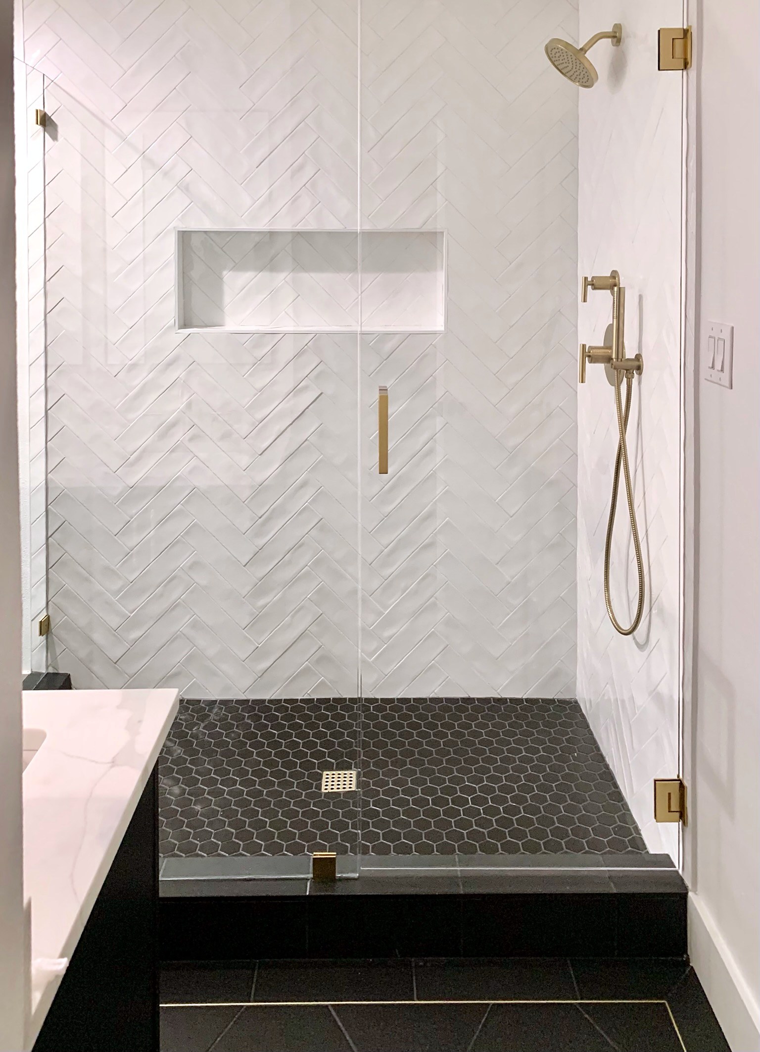 Summer Glen renovation — shower with herringbone tile and gold fixtures
