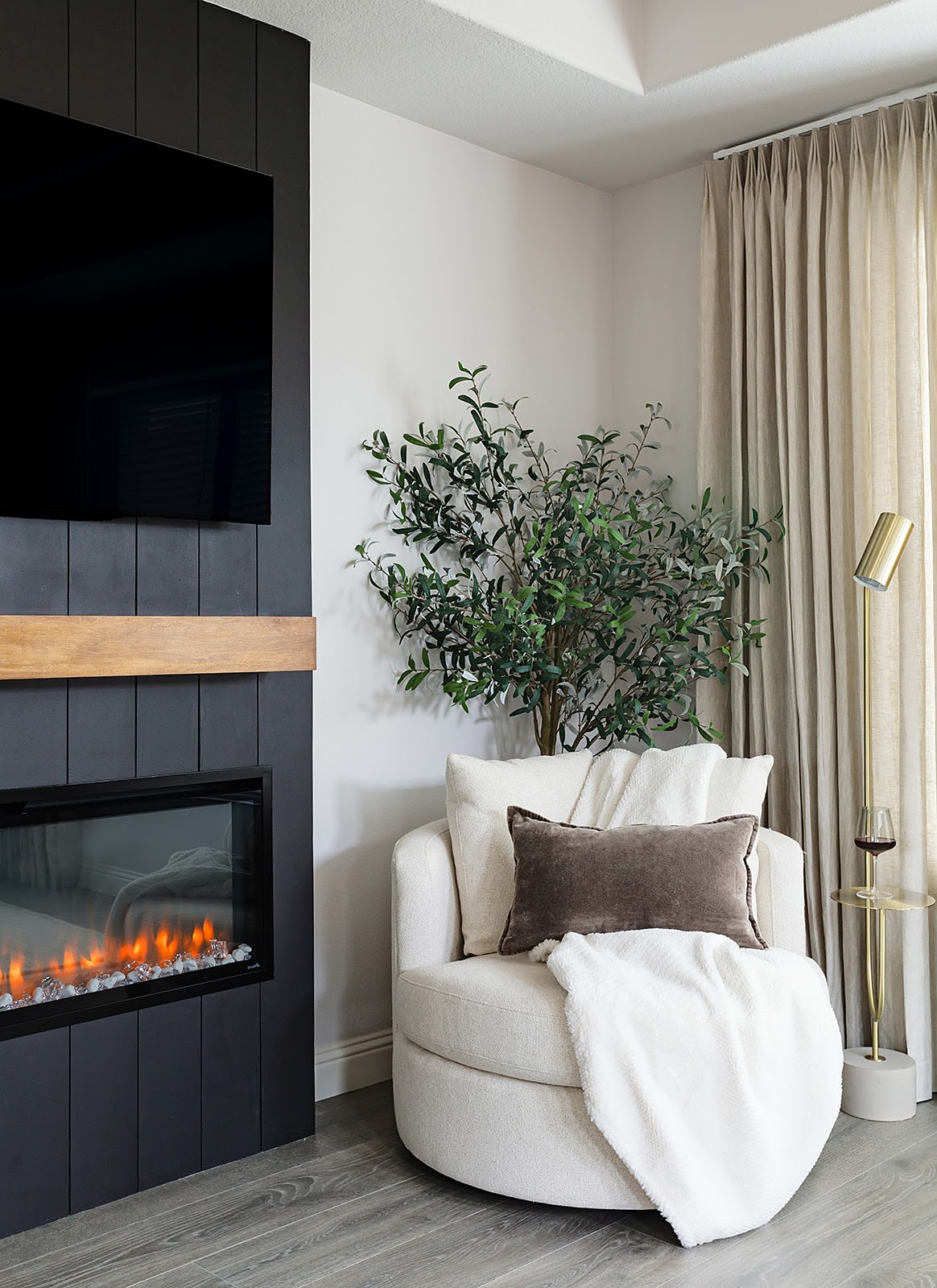 Strait Lane — cozy accent chair by the black fireplace with green olive tree