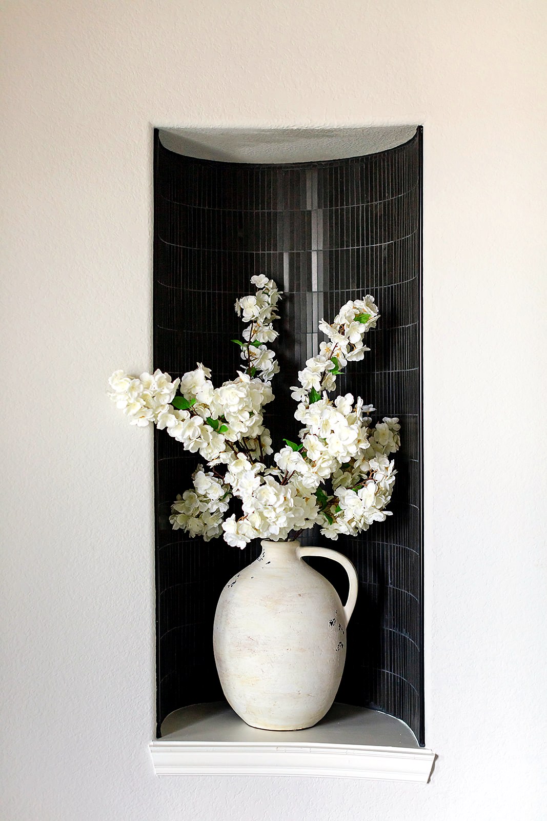 Strait Lane — tiled black entry niche with floral arrangement