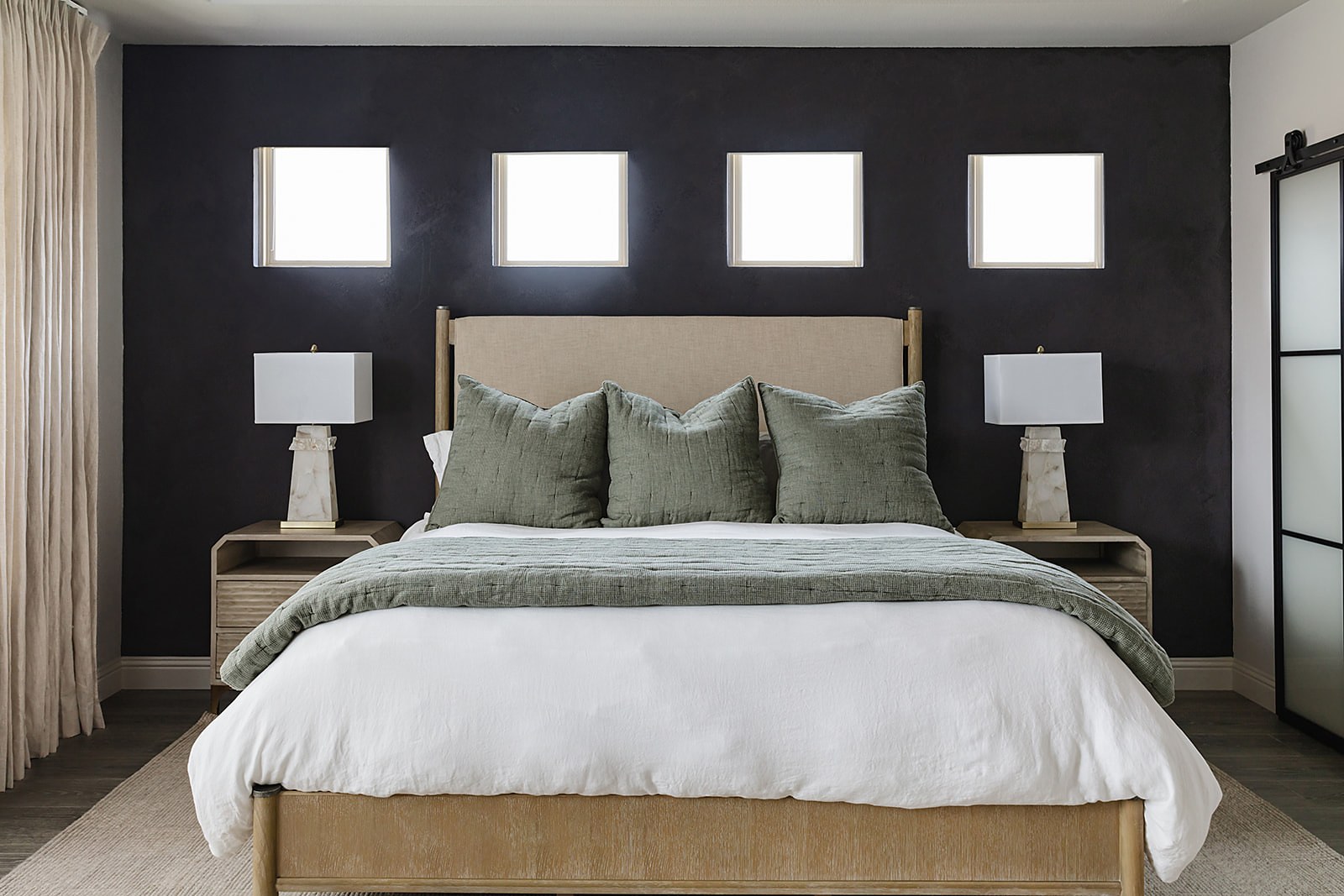 Strait Lane primary bedroom — paneled ceiling, black accent wall and upholstered bed