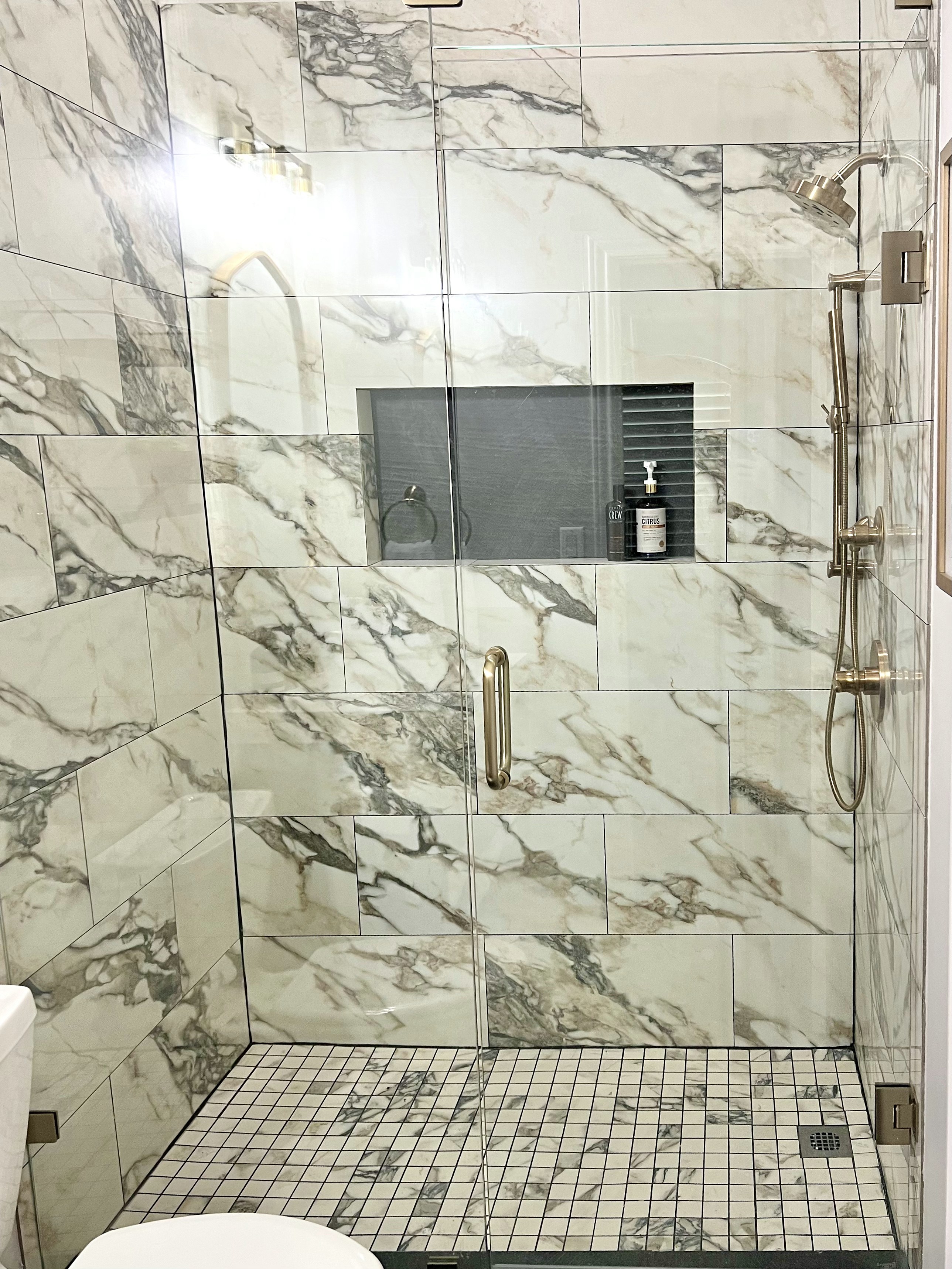 Shady Oaks — masculine bathroom marble shower with glass enclosure, mosaic floor tile and brass fixtures
