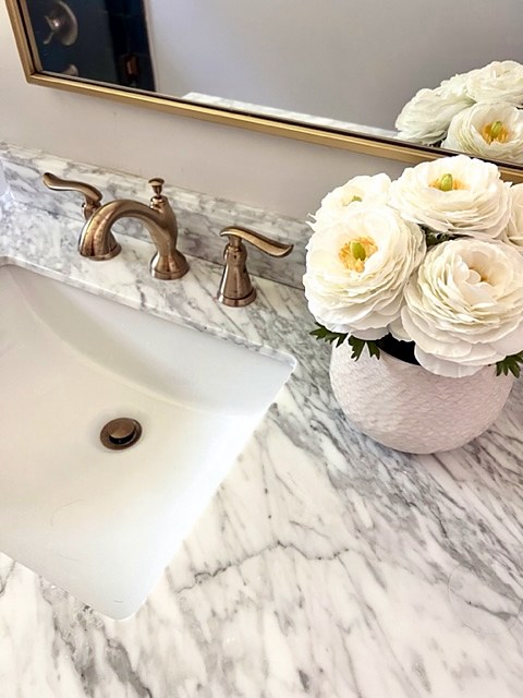Shady Oaks — feminine bathroom marble vanity countertop with brass faucet and white ranunculus