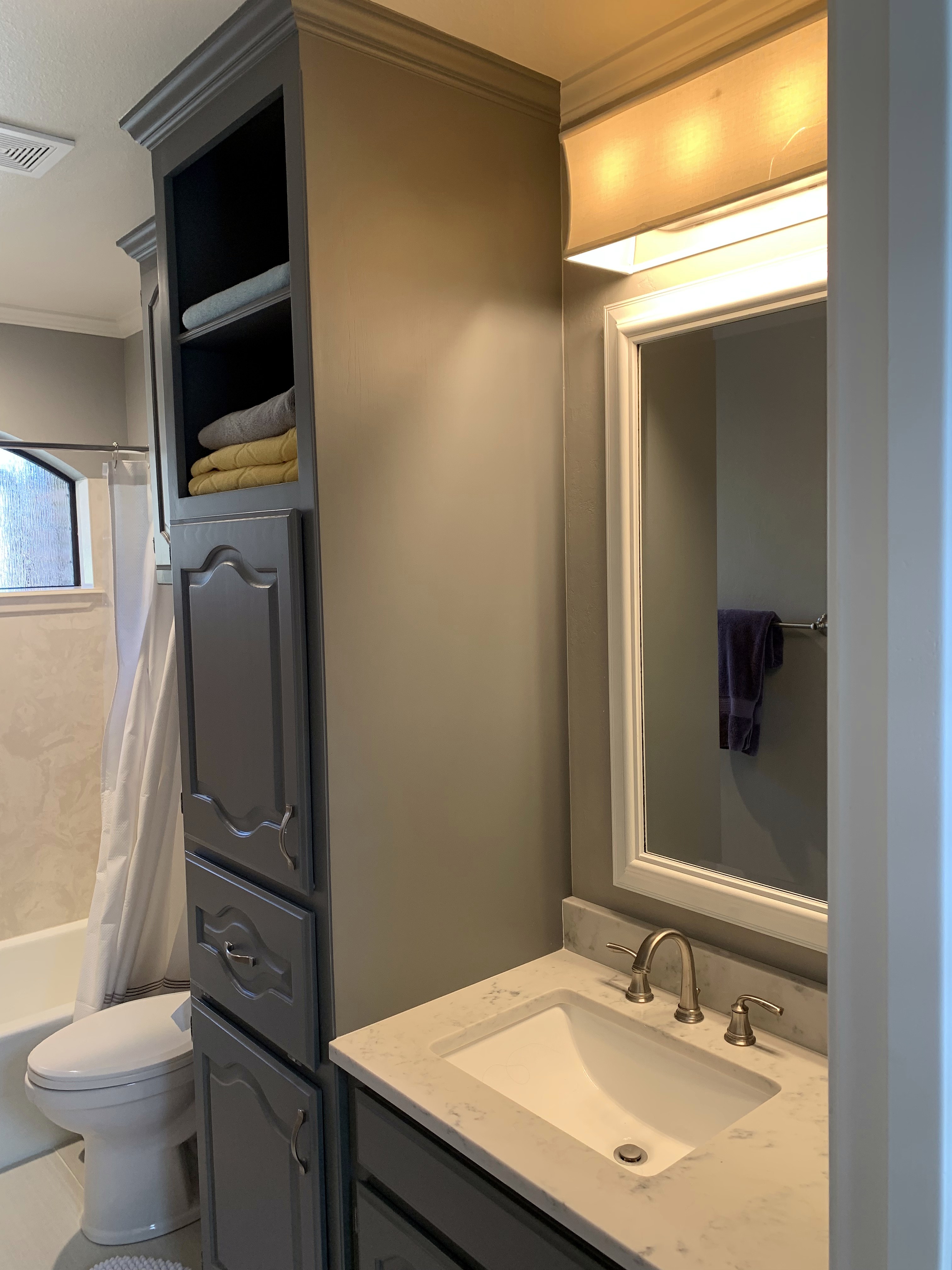 Shady Oaks — feminine bathroom before renovation, original gray cabinetry, marble countertop and linen tower
